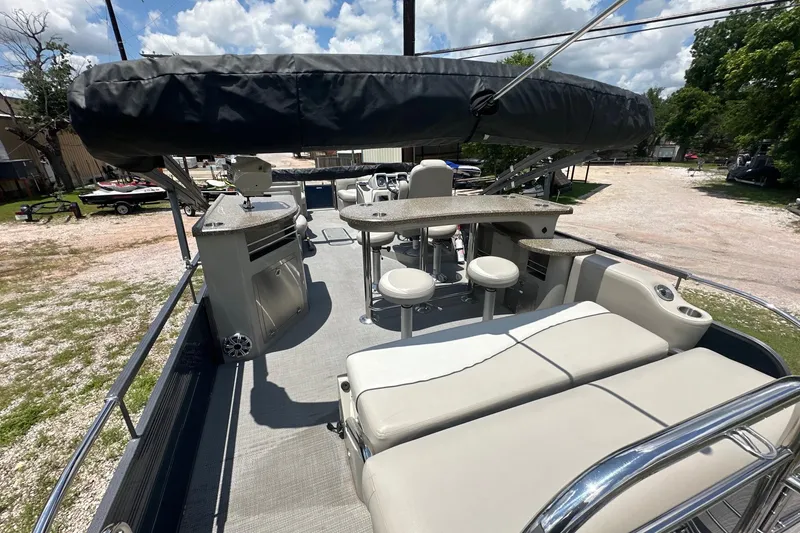 Slide: The Image of 2017 Manitou 25 SES pontoon boat interior with seating and bar area under canopy. - 7
