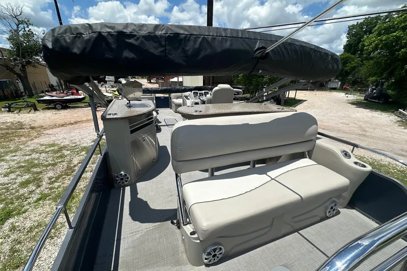 Slide: The Image of 2017 Manitou 25 SES pontoon boat interior with seating and helm, under a sunny sky. - 9