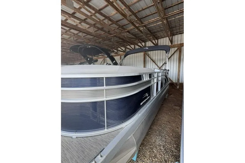 Slide: The Image of 2022 Bennington 22 SLX pontoon boat stored in a metal-roofed shed. - 2