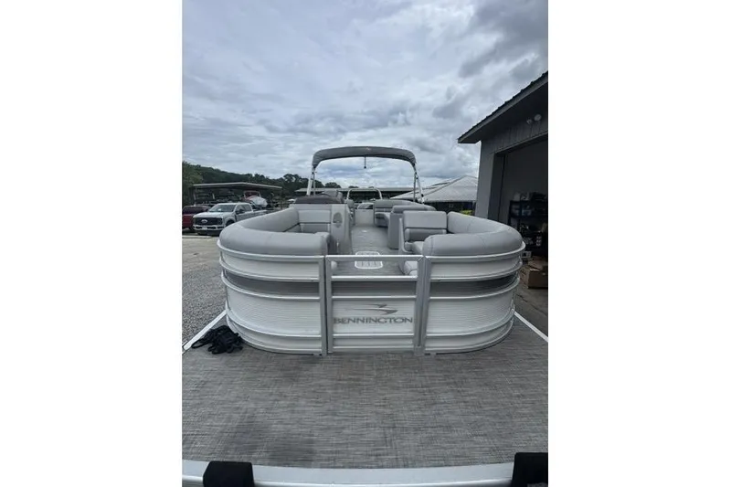 Slide: The Image of 2021 Bennington 24 LRSC pontoon boat with gray seating, docked under cloudy skies. - 2