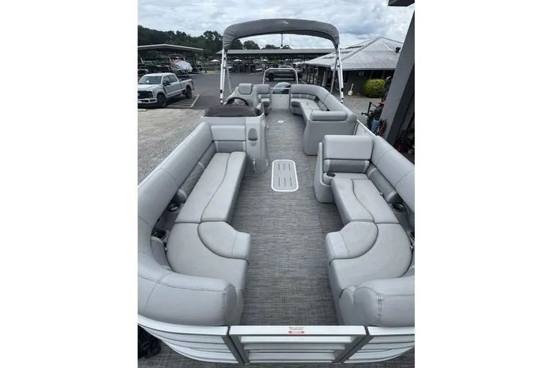 Slide: The Image of 2021 Bennington 24 LRSC pontoon boat with spacious seating and canopy, parked outdoors. - 4