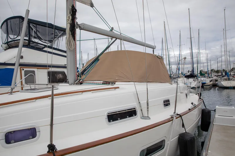 Slide: The Image of 1999 Beneteau Oceanis 36 CC sailboat docked in a marina, featuring a beige canopy. - 2