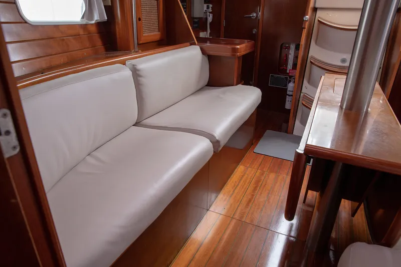 Slide: The Image of Interior of 1999 Beneteau Oceanis 36 CC yacht with wooden flooring and white cushioned seating. - 22