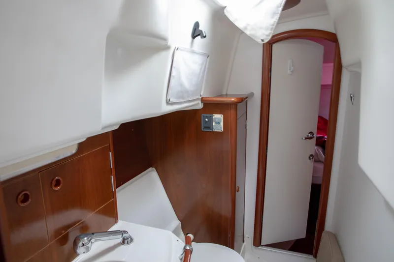 Slide: The Image of Interior of 1999 Beneteau Oceanis 36 CC yacht, featuring a compact bathroom with wooden accents. - 32