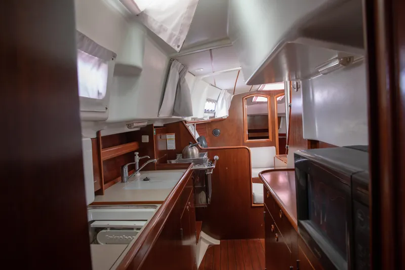 Slide: The Image of Interior of 1999 Beneteau Oceanis 36 CC sailboat, featuring a compact kitchen and cozy seating area. - 37
