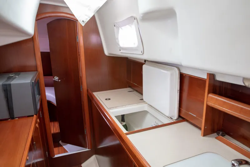 Slide: The Image of Interior of 1999 Beneteau Oceanis 36 CC sailboat, featuring wooden cabinetry and compact kitchen area. - 43