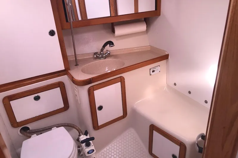 Slide: The Image of 2000 Catalina 36 MkII yacht bathroom with sink, toilet, and wooden cabinetry. - 8