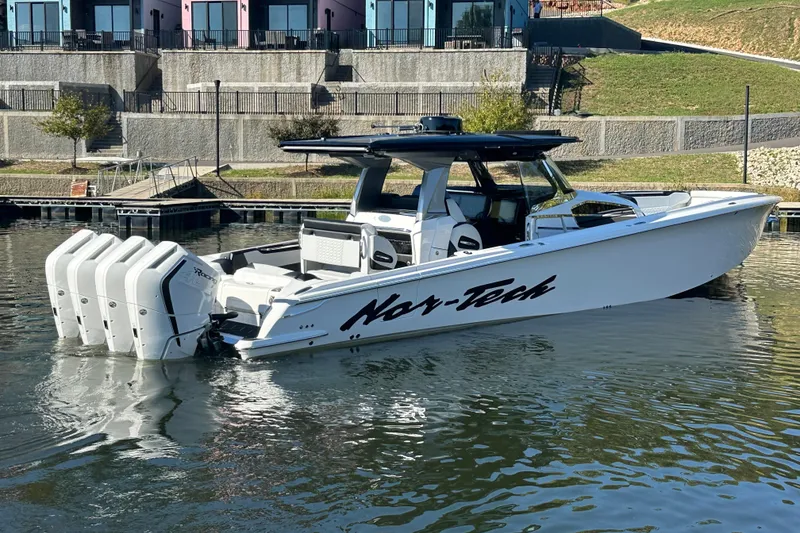 Slide: The Image of 2025 Nor-Tech 450 Sport Center Console boat on calm water near a dock. - 18