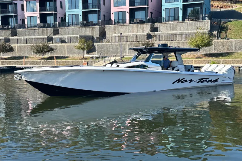 Slide: The Image of 2025 Nor-Tech 450 Sport Center Console boat docked near colorful buildings. - 3