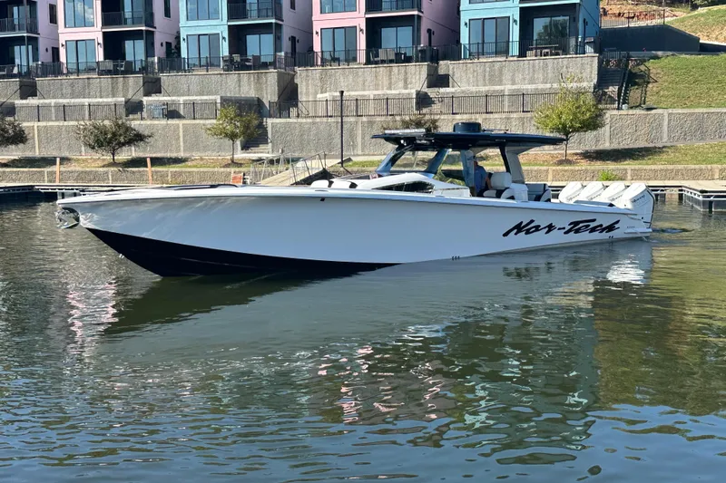 Slide: The Image of 2025 Nor-Tech 450 Sport Center Console boat docked near colorful buildings. - 4