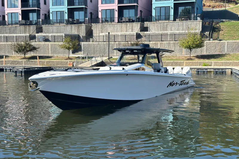 Slide: The Image of 2025 Nor-Tech 450 Sport Center Console boat docked near colorful waterfront buildings. - 7