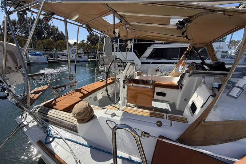 Slide: The Image of 2010 Beneteau Oceanis 37 sailboat cockpit with tan cushions and marina backdrop. - 20