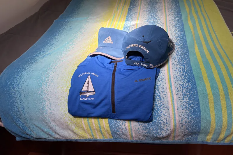 Slide: The Image of Blue "California Dream" racing team apparel on striped towel, featuring Adidas cap and Terrex jacket. - 70