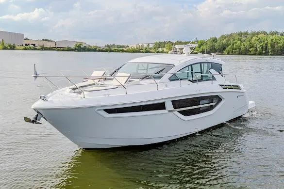 Slide: The Image of 2023 Cruisers Yachts 42 Cantius on a serene lake with lush green shoreline. - 1