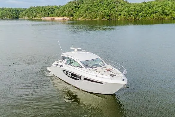 Slide: The Image of 2023 Cruisers Yachts 42 Cantius on serene lake with lush green shoreline. - 11