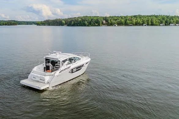 Slide: The Image of 2023 Cruisers Yachts 42 Cantius on a serene lake with lush green shoreline. - 15