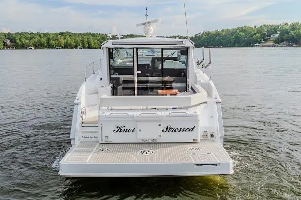 Slide: The Image of 2023 Cruisers Yachts 42 Cantius on serene lake, rear view with "Knot Stressed" name. - 18