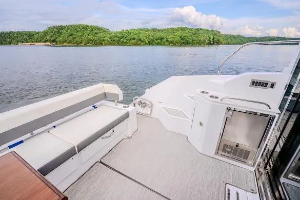 Slide: The Image of 2023 Cruisers Yachts 42 Cantius deck with seating, overlooking serene water and lush greenery. - 33