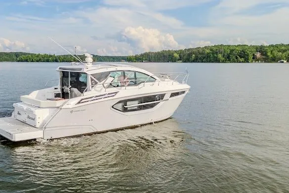 Slide: The Image of 2023 Cruisers Yachts 42 Cantius on serene lake with lush green shoreline. - 5