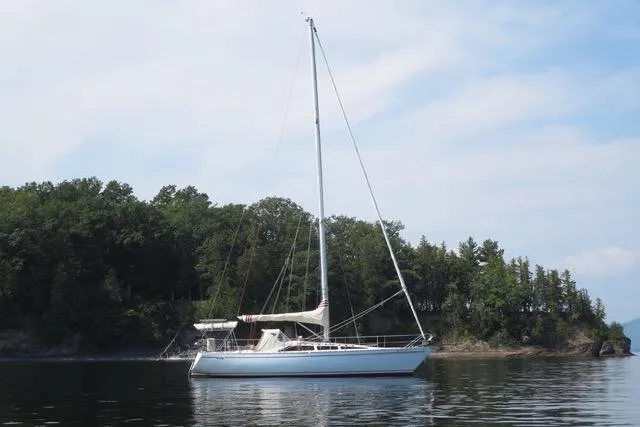 Slide: The Image of 1981 Yamaha 36 sailboat anchored on calm water near a forested shoreline. - 7