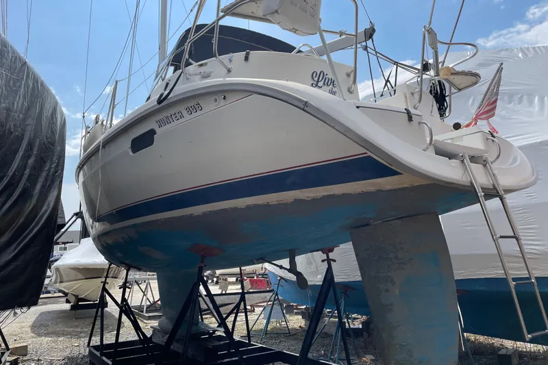 Slide: The Image of 1995 Hunter 336 sailboat on stands, with visible keel and ladder, in a boatyard. - 3