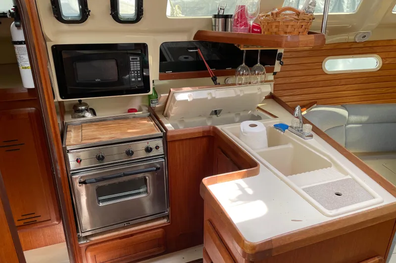 Slide: The Image of 1995 Hunter 336 yacht kitchen with stove, microwave, and sink in a compact layout. - 9