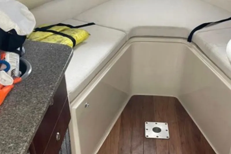 Slide: The Image of 2017 Robalo R265 Walkaround cabin interior with cushioned seating and wooden flooring. - 30