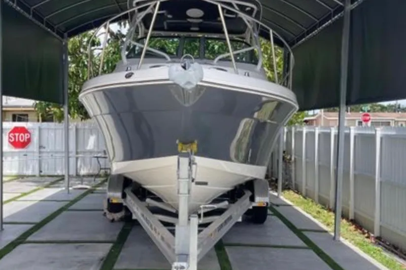 Slide: The Image of 2017 Robalo R265 Walkaround boat on trailer under canopy, with stop sign nearby. - 11