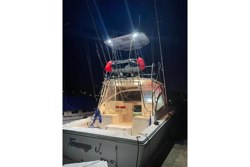 Slide: The Image of 2008 Luhrs 28 Open boat illuminated at night, docked with fishing rods visible. - 19