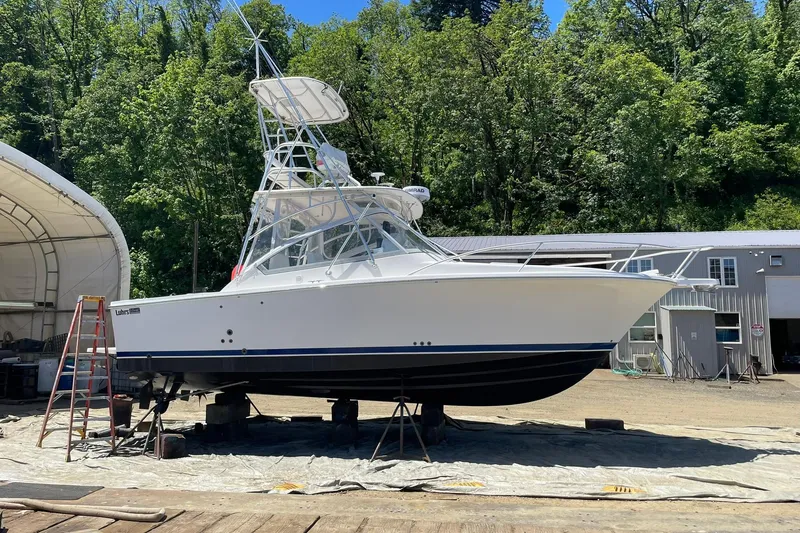 Slide: The Image of 2008 Luhrs 28 Open boat on dry dock, surrounded by trees and buildings. - 30