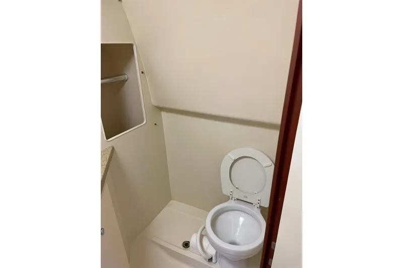 Slide: The Image of 2008 Luhrs 28 Open boat bathroom with toilet and storage shelf. - 4