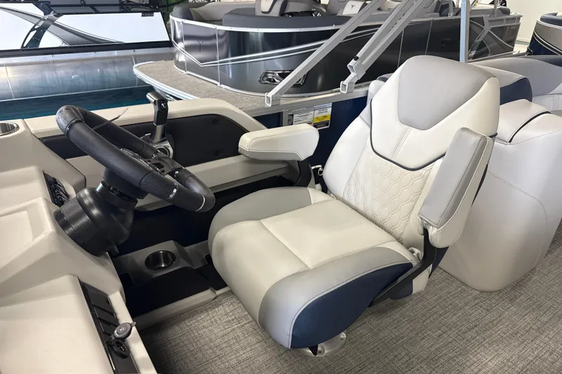 Slide: The Image of 2026 Tahoe Pontoon LTZ Quad Lounger captain's chair and steering wheel in a showroom. - 9