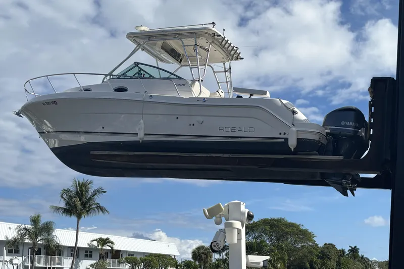 Slide: The Image of 2014 Robalo R305 Walkaround boat lifted, showcasing sleek design and Yamaha engines. - 2