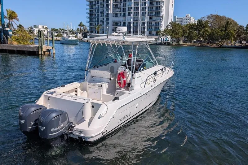 Slide: The Image of 2014 Robalo R305 Walkaround boat with dual Yamaha engines on a sunny waterfront. - 5