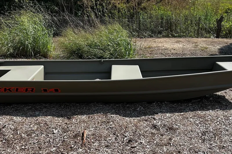 The Image of 2026 Tracker Grizzly 14 Jon boat on dry ground, surrounded by greenery. - 0