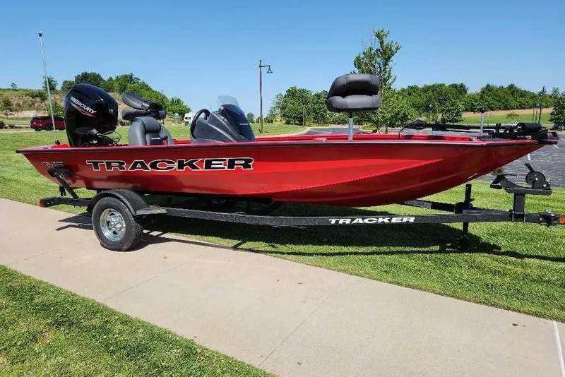 The Image of 2026 Tracker Pro Team 175 boat on trailer, vibrant red, parked on grass. - 0