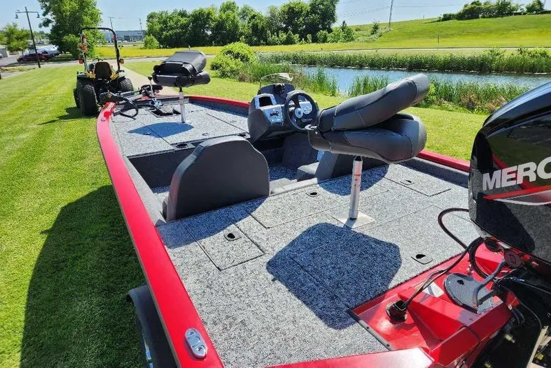 Slide: The Image of 2026 Tracker Pro Team 175 boat with Mercury engine on grassy area near water. - 2