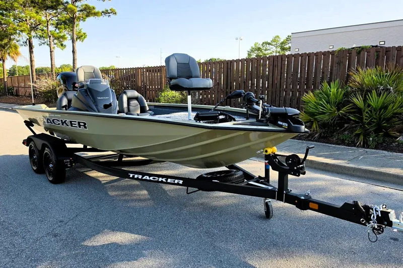 Slide: The Image of 2026 Tracker Pro Team 195 boat on trailer, parked on street, surrounded by trees and fence. - 4