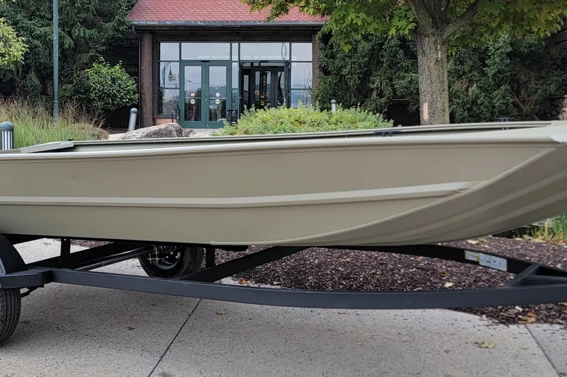 The Image of 2026 Tracker Grizzly 1754 Utility boat on trailer, parked outdoors near greenery. - 0