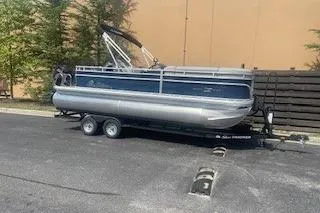 Slide: The Image of 2026 Sun Tracker SportFish 20 DLX pontoon boat on trailer in parking lot. - 2