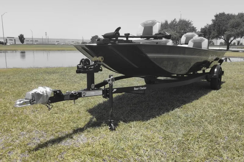 The Image of 2026 Tracker Bass Tracker Classic XL boat on trailer, parked on grassy area near water. - 0