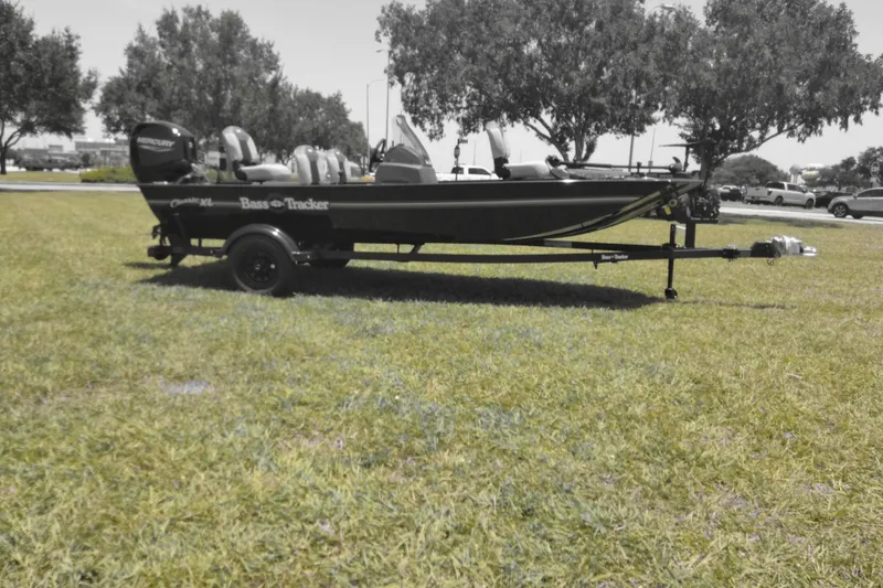 Slide: The Image of 2026 Tracker Bass Tracker Classic XL boat on grassy field with trees in background. - 9