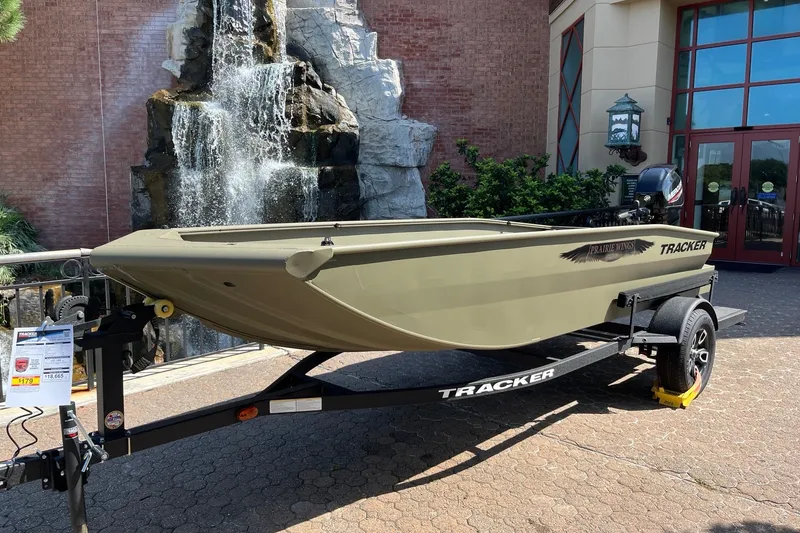 The Image of 2026 Tracker Grizzly 1650 T Prairie Wings Edition boat displayed outdoors near a waterfall. - 0