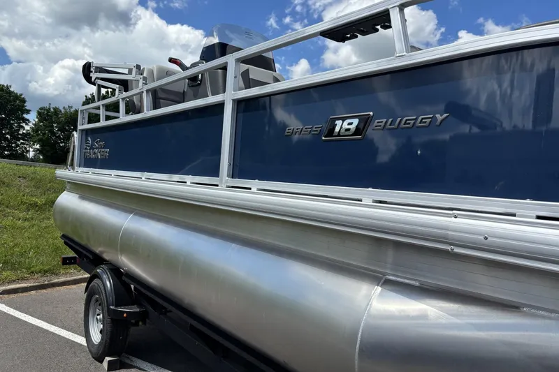Slide: The Image of 2026 Sun Tracker Bass Buggy 18 DLX pontoon boat on trailer under blue sky. - 3