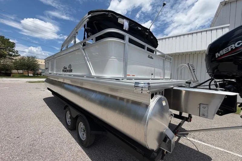 Slide: The Image of 2026 Sun Tracker Party Barge 22 RF DLX pontoon boat on trailer, parked outdoors. - 2
