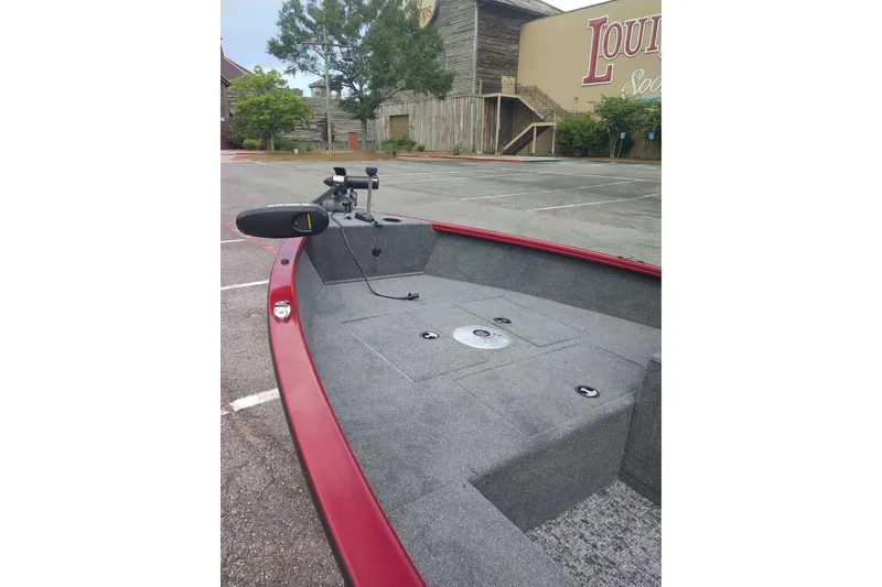 Slide: The Image of 2026 Tracker Super Guide V-16 SC boat with red trim in a parking lot. - 4