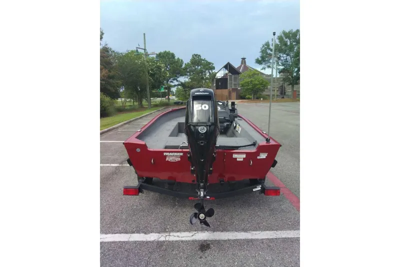 Slide: The Image of Red 2026 Tracker Super Guide V-16 SC boat with Mercury outboard motor in parking lot. - 2