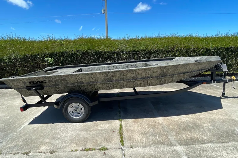 The Image of 2026 Tracker Grizzly 1754 Utility boat on trailer, parked outdoors under clear blue sky. - 0