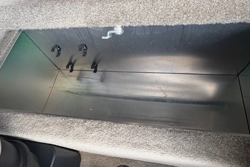 Slide: The Image of An empty storage compartment inside a boat with gray carpeting. - 12