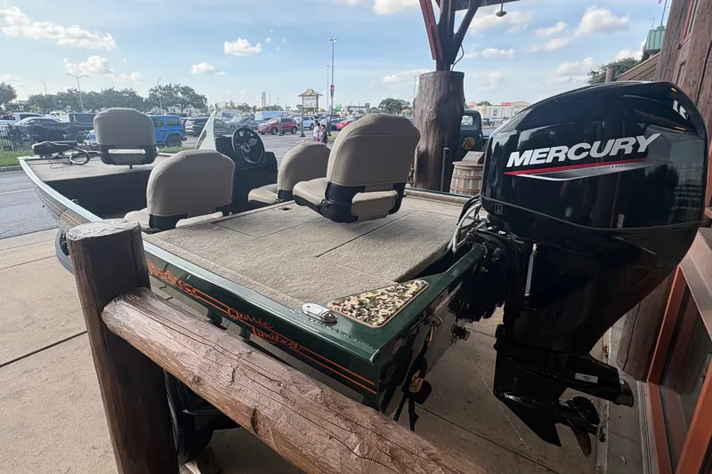 Slide: The Image of A 2026 Tracker Bass Tracker Classic Limited boat with a Mercury outboard motor, parked at a dock. - 2